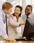 Three people around a computer monitor.